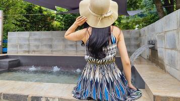 Guests can unwind by the serene water feature, surrounded by lush greenery and a shaded area.