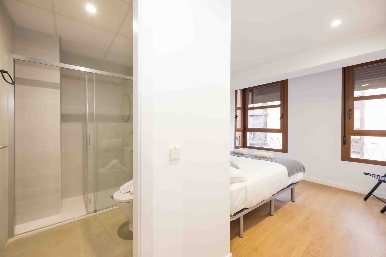 A modern bedroom with a bed, a small table, and a window.