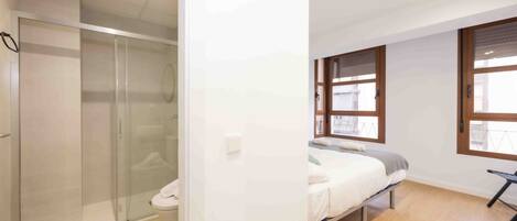 A modern bedroom with a bed, a small table, and a window.