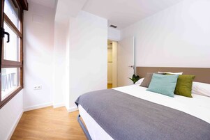 Un dormitorio con cama, ventana y puerta que da a otra habitación.