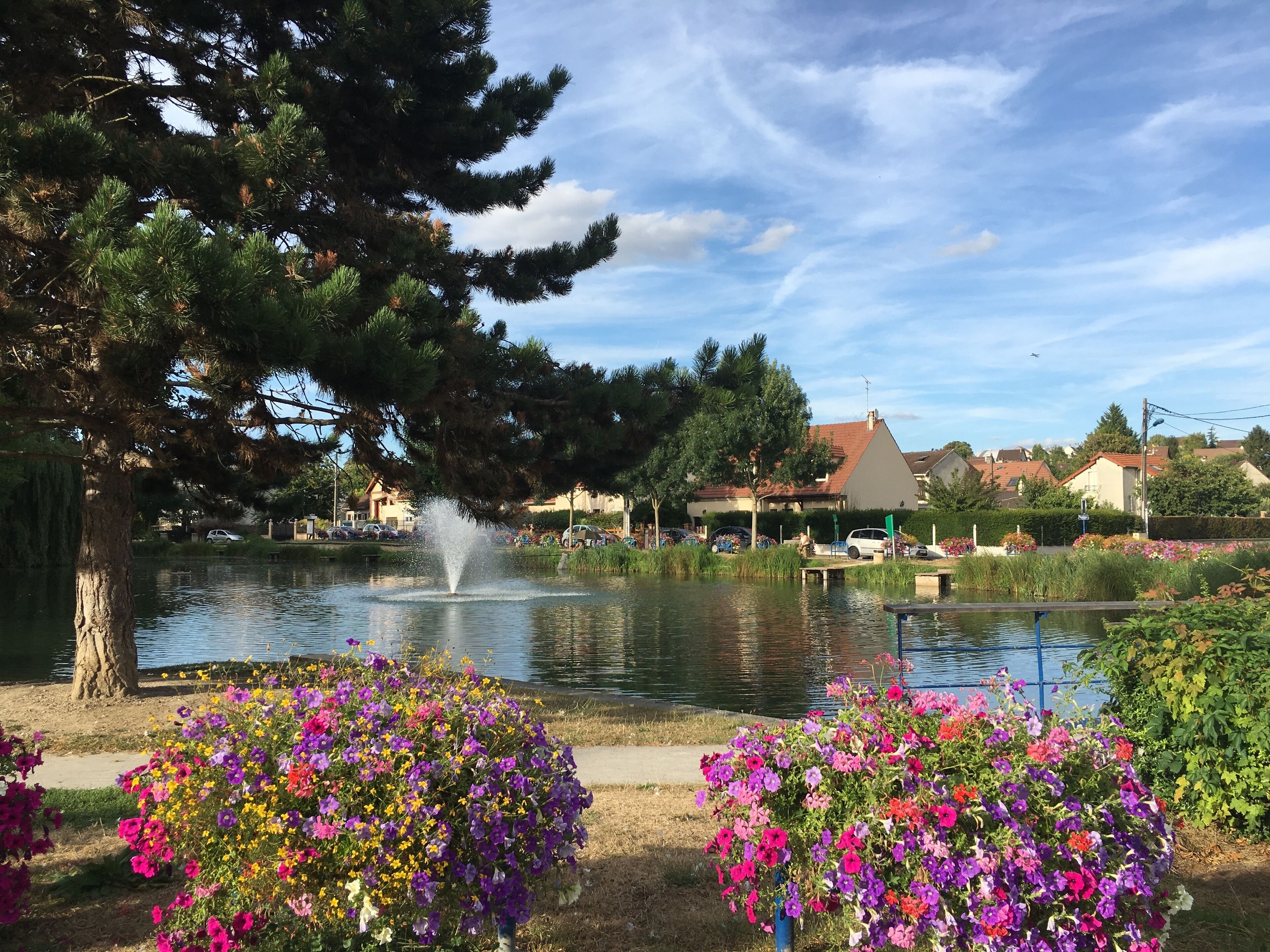 Un parque con un estanque, flores coloridas y una fuente.