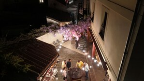 An outdoor courtyard with a seating area, a staircase, and a decorative tree with purple flowers. - Hôtel Le Celtic (Le Thillay)
