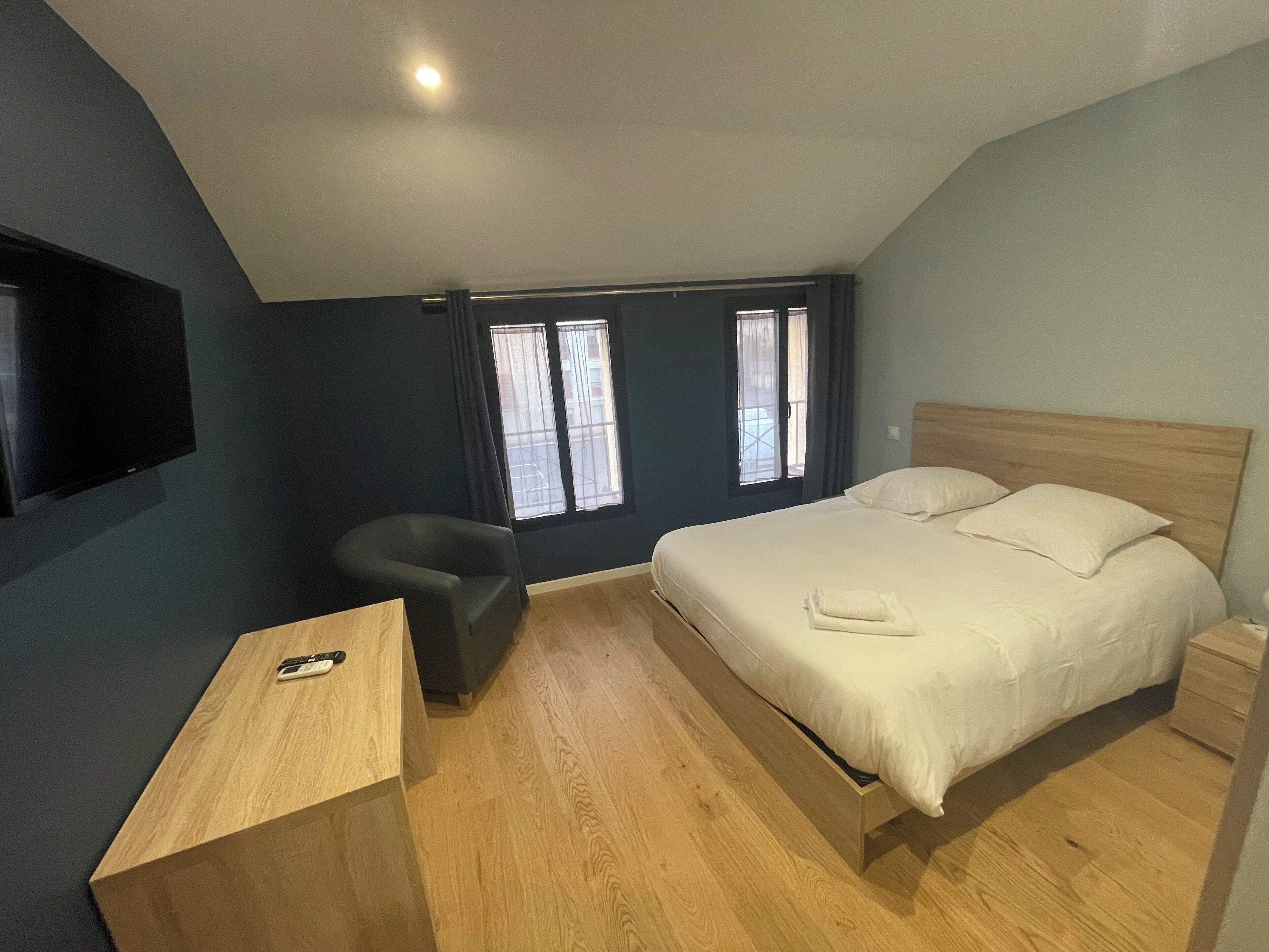Een slaapkamer met een bed, een bureau, een stoel en een televisie aan de muur.