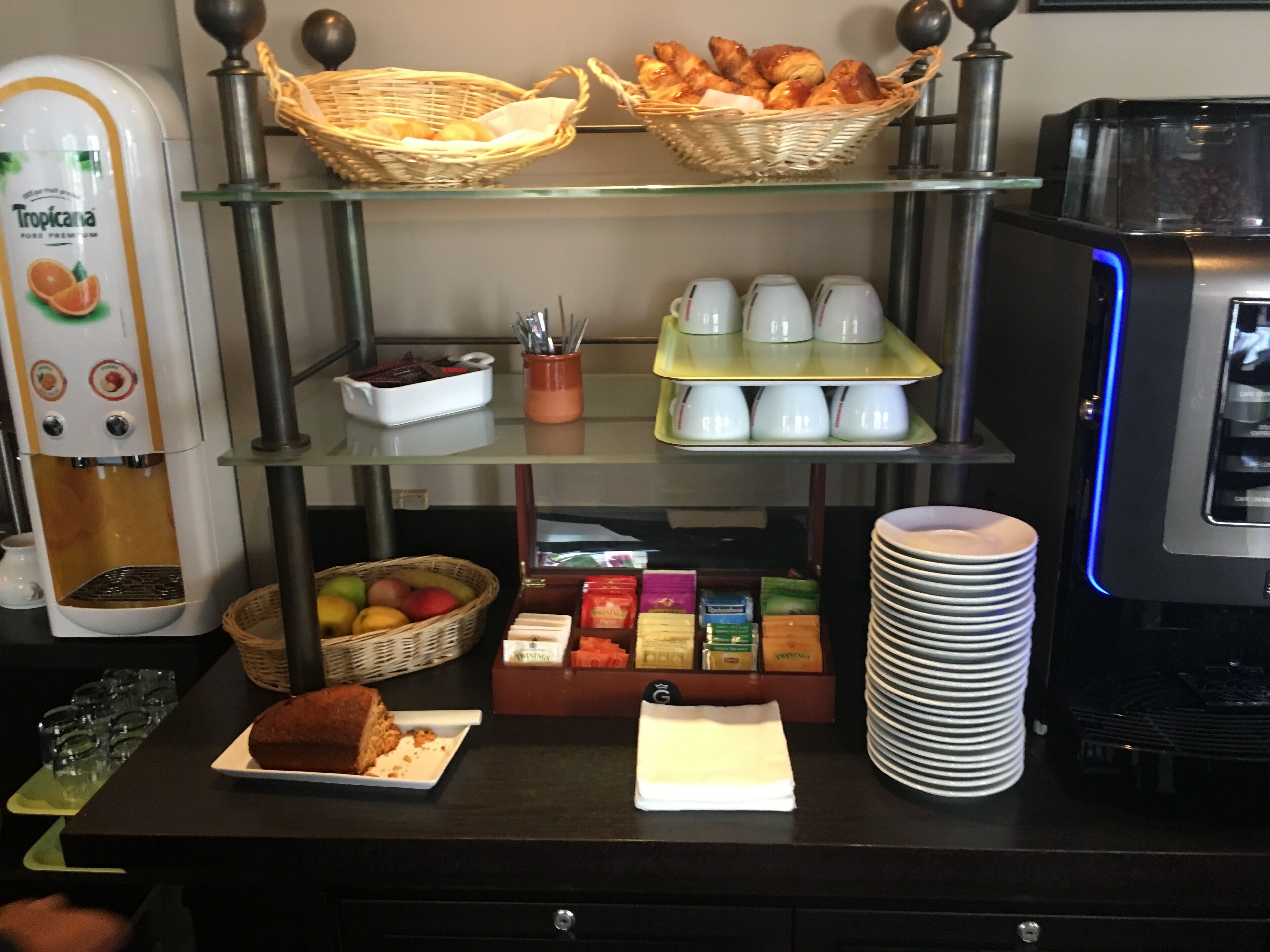 Montaje de un bufé de desayuno con diversas opciones de comida, máquinas de café y vajillas de té.
