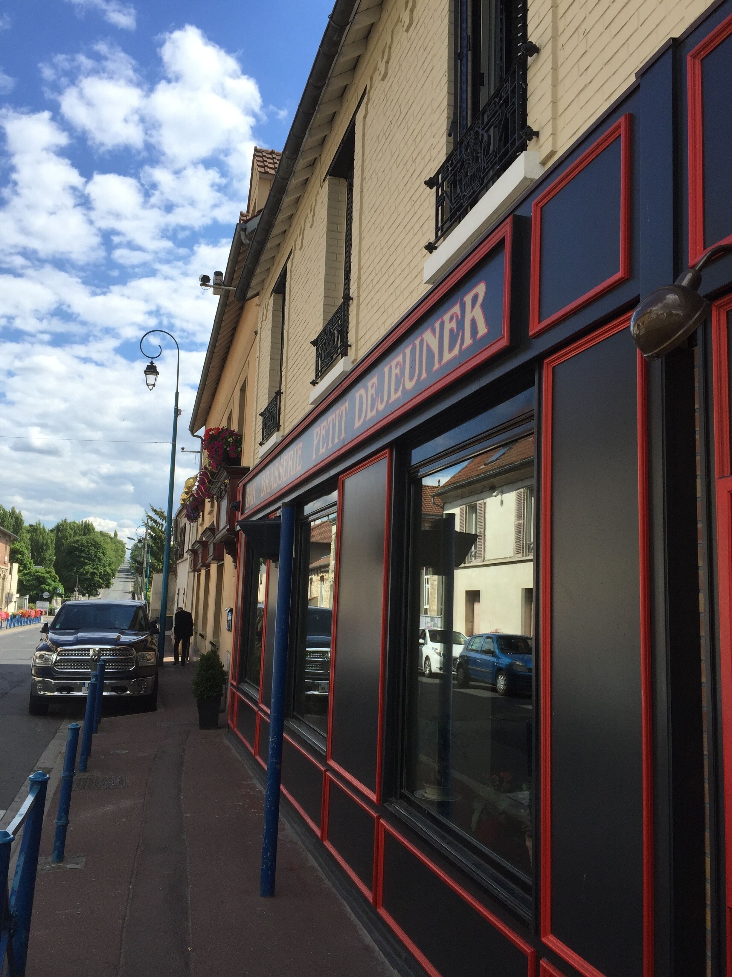 A building with a sign reading "Petit Dejeuner" and a black SUV parked in front.
