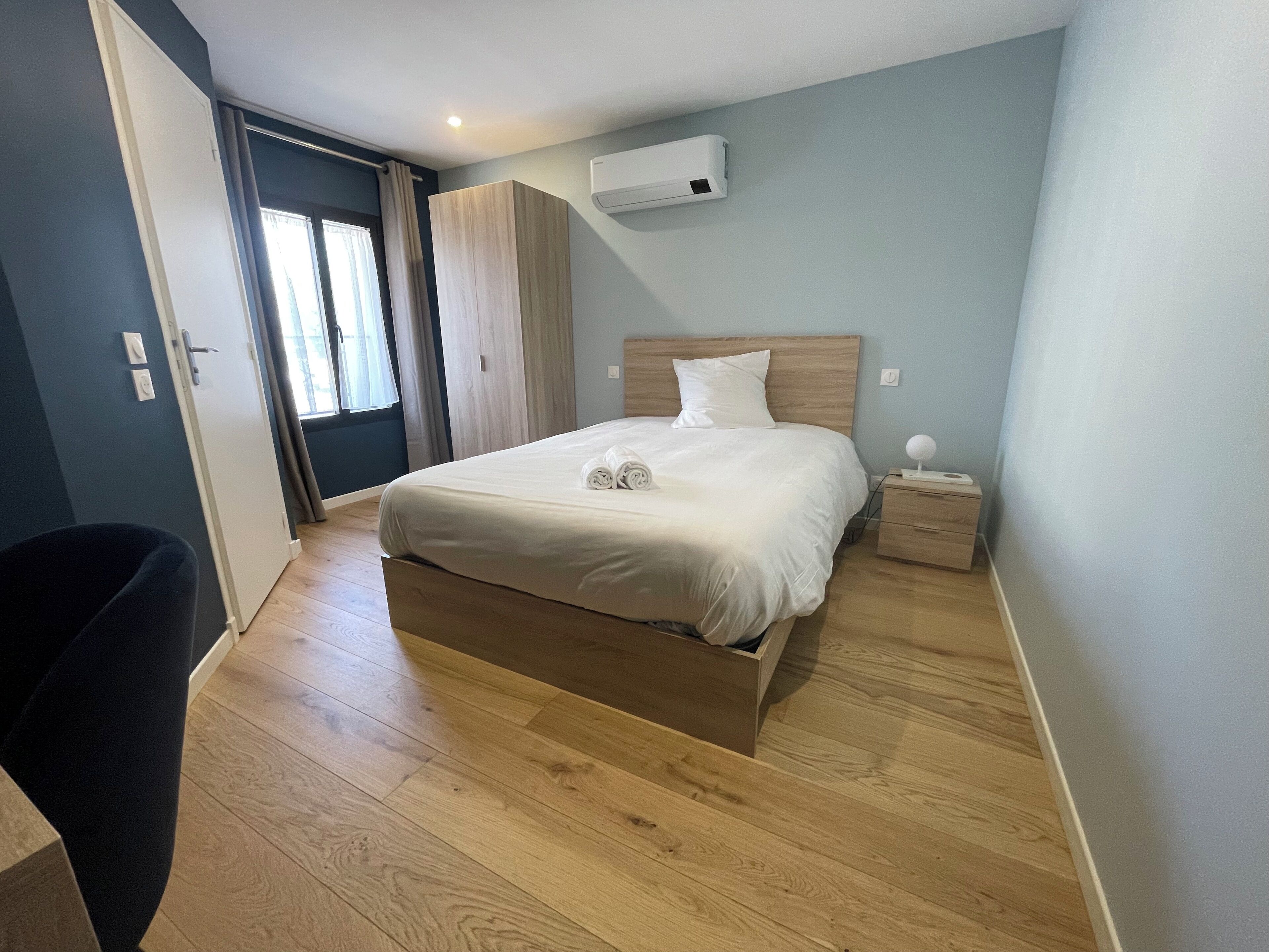 Une chambre à coucher bien rangée, avec un lit en bois, une table de chevet avec une lampe et une armoire.
