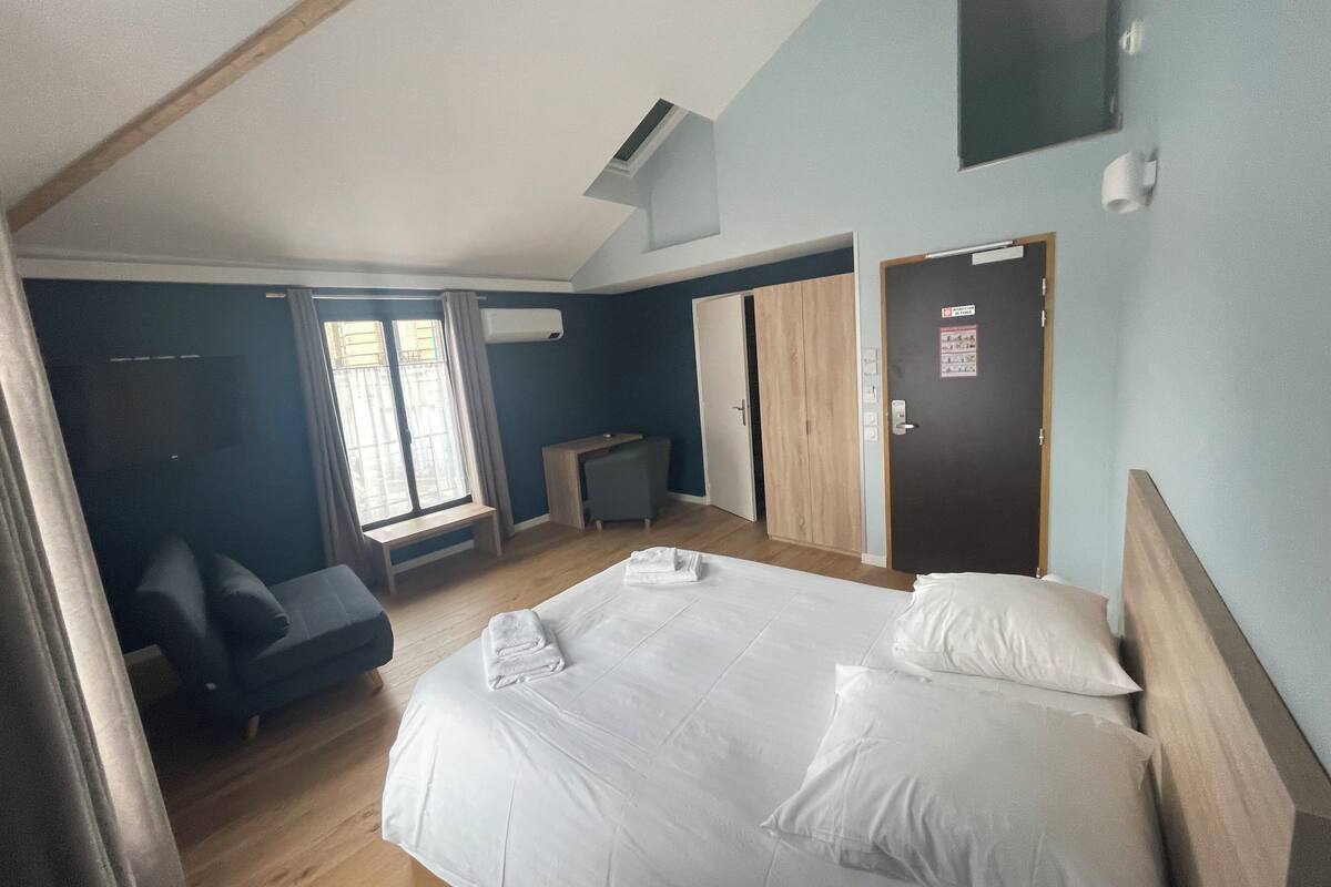 A bedroom with a bed, a desk, a chair, a wardrobe, and a door.