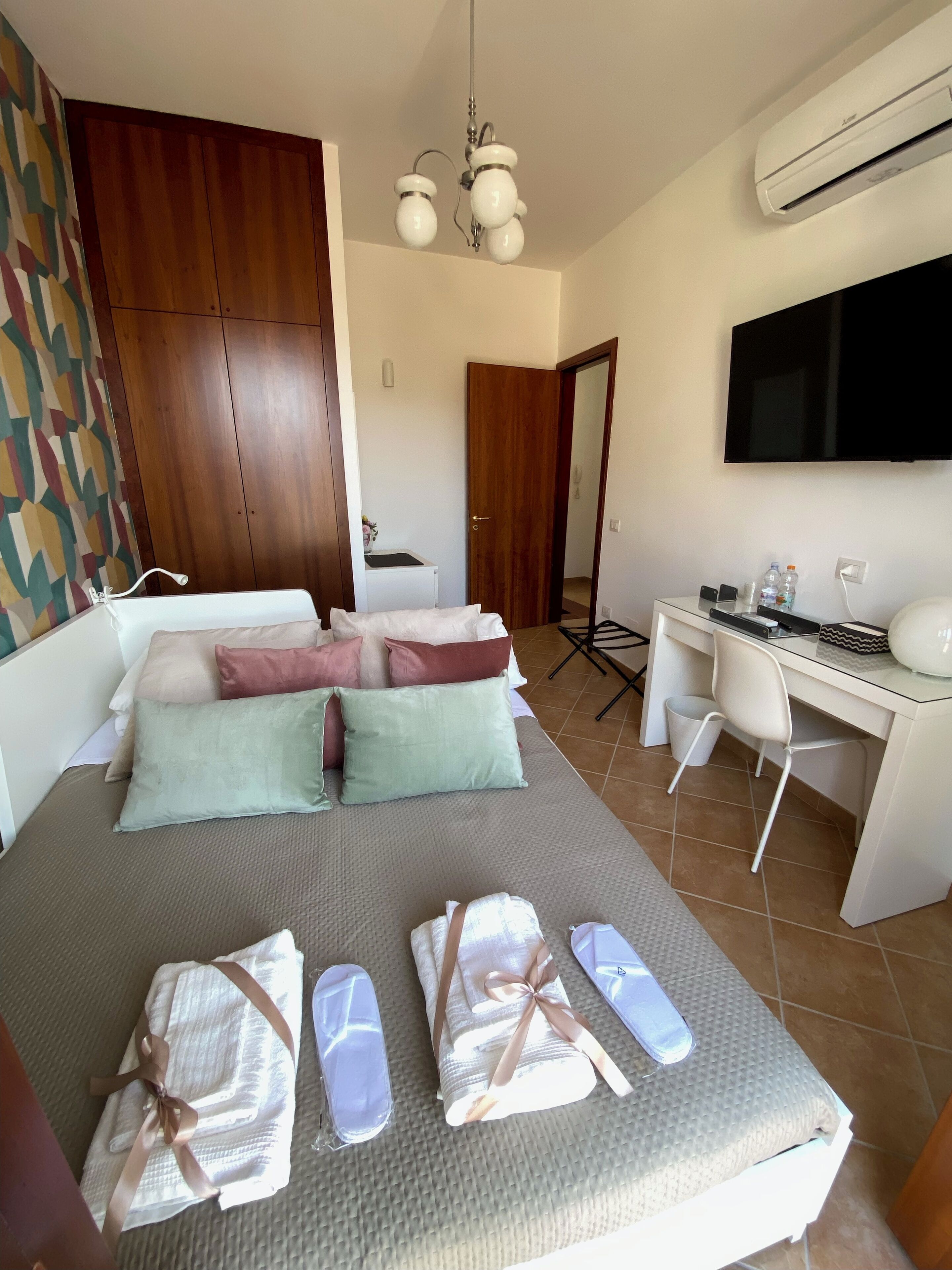 Una camera d'albergo con un letto, una scrivania, una sedia, un condizionatore d'aria e una televisione.