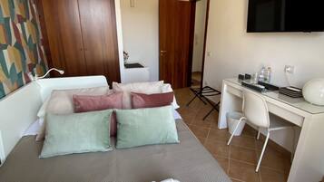 Una camera d'albergo con un letto, una scrivania, una sedia, un condizionatore d'aria e una televisione.