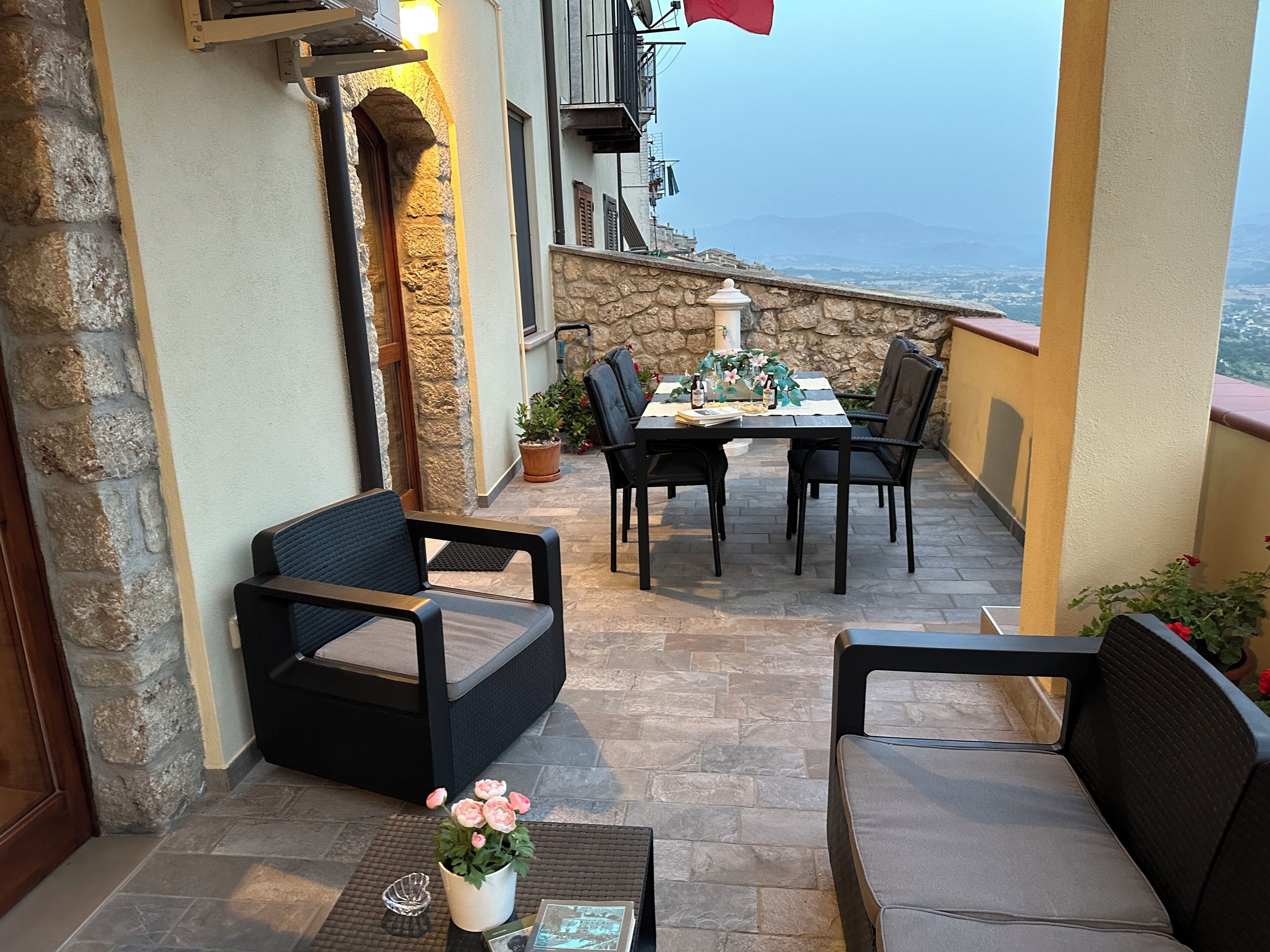 A patio with stone walls, a table set for two, and outdoor seating.