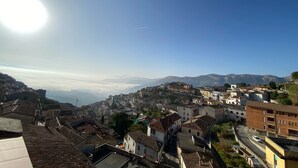 Vista panorámica de un pueblo con cielo despejado, que presenta una mezcla de edificios tradicionales y modernos, y una imponente cadena montañosa al fondo.