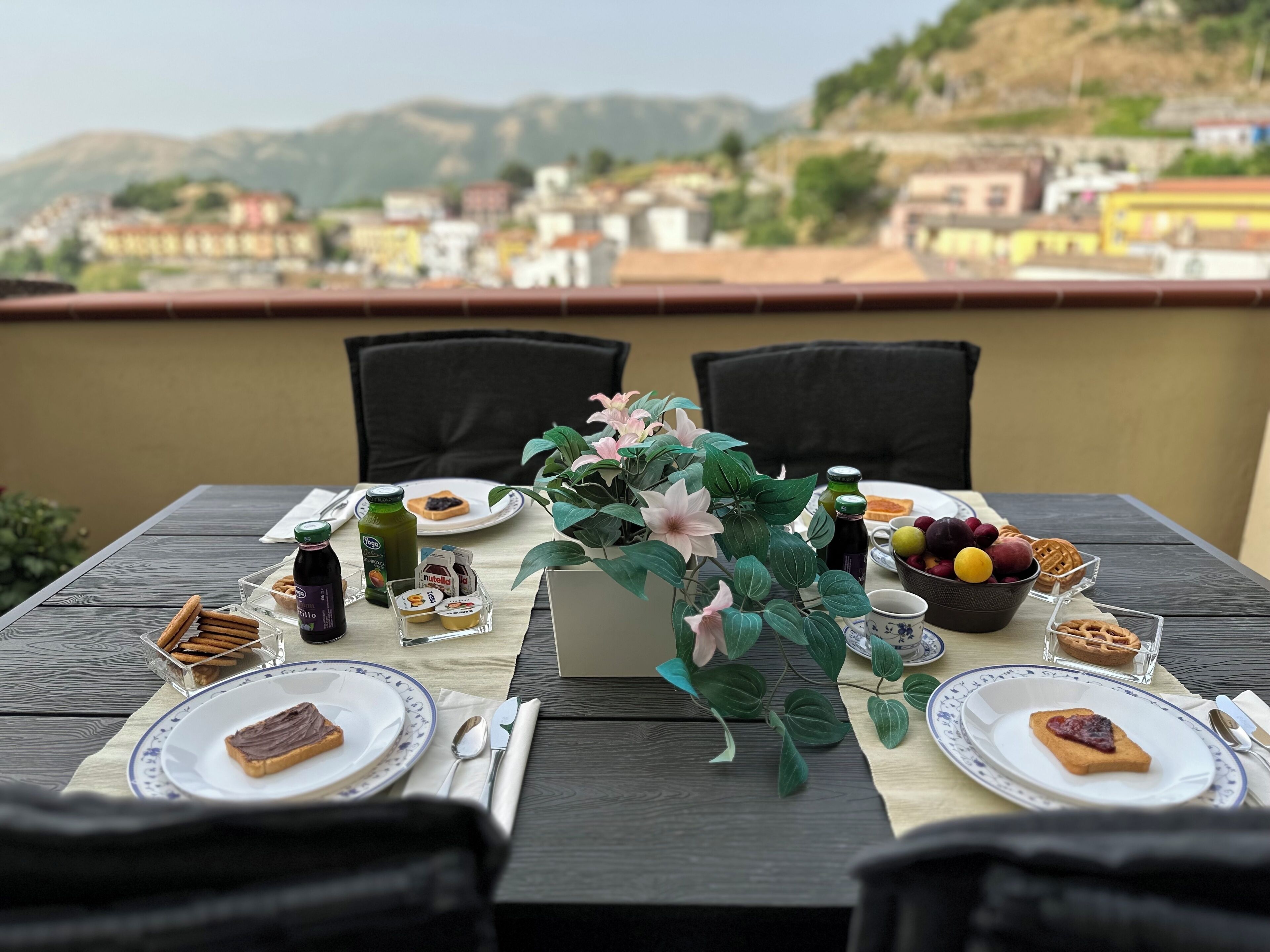 Una mesa para dos, con platos de comida, una botella de jugo y un jarrón de flores.
