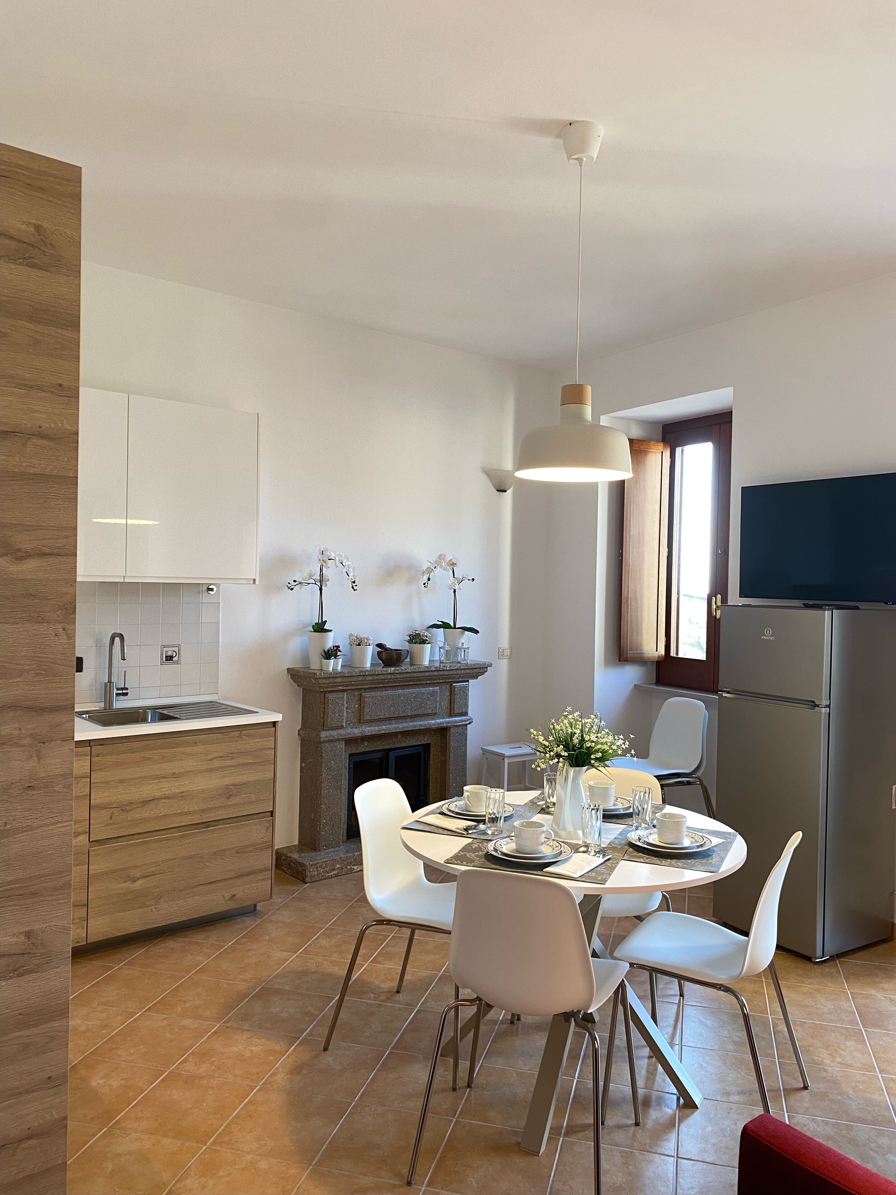 Una cucina moderna con mobili bianchi, un forno integrato e un'area pranzo con tavolo apparecchiato per due.