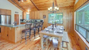 A wooden cabin interior with a kitchen, dining area, and large windows. - Quiet Cabin w/ Deck: Near Lake Almanor! (Westwood)