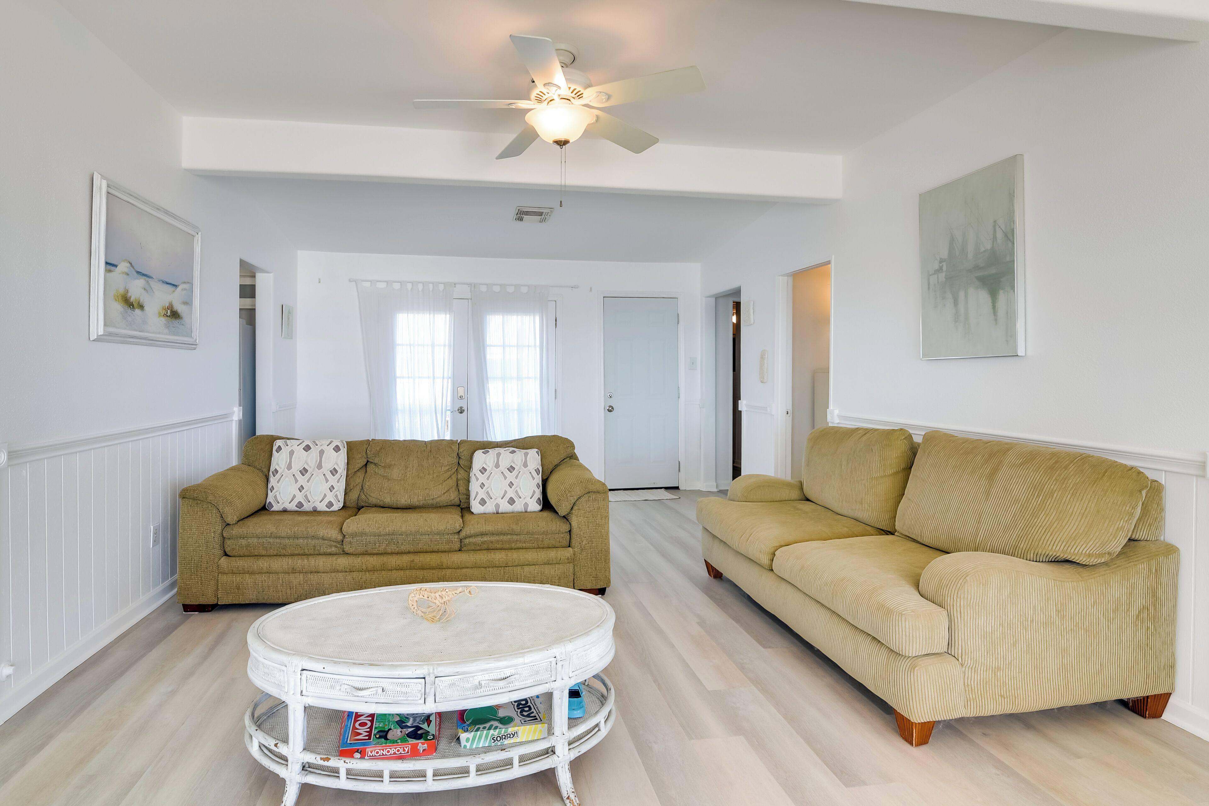 A living room with two sofas, a round coffee table, and a ceiling fan.