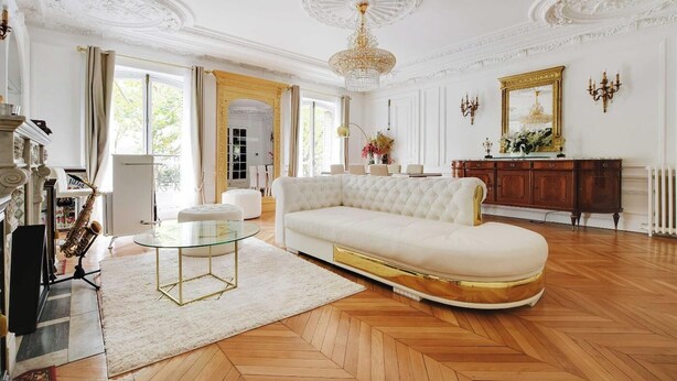 Un salon spacieux avec un canapé blanc, une table basse en verre et une cheminée.