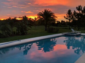 A swimming pool with a sunset view, surrounded by greenery and a lawn. - Swiss 53-lake Denise (Clermont)