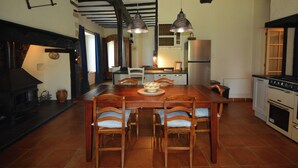 A spacious kitchen with a large wooden table and chairs, a built-in oven, and hanging pendant lights. - Charming Hydrangea Cottage 3 stars, with lovely views of the countryside and hills, quiet and locate (Savignac-Lédrier)