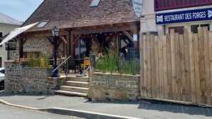 A rustic stone building with a wooden roof and a sign for 'Bar Restaurant des Forges'. - Charming Hydrangea Cottage 3 stars, with lovely views of the countryside and hills, quiet and locate (Savignac-Lédrier)