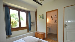 A bedroom with a bed, a window with curtains, a wooden dresser, and a door leading to a bathroom. - Charming Hydrangea Cottage 3 stars, with lovely views of the countryside and hills, quiet and locate (Savignac-Lédrier)