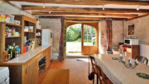 Una cocina rústica con vigas de madera a la vista, una pared de piedra y un gran puerta de madera que da al exterior.