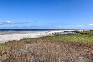 A coastal landscape with a sandy beach, grassy areas, and a clear blue sky. - Beach & Pool Access: Tranquil Hilton Head Getaway (Hilton Head Island)