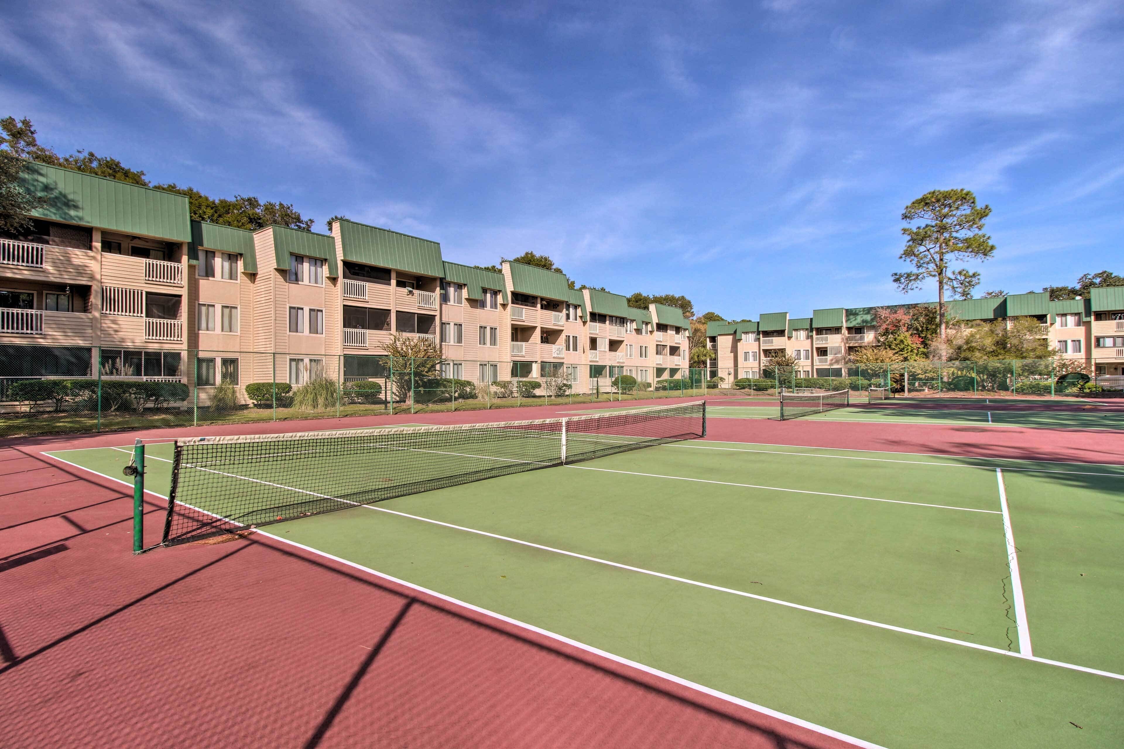 A tennis court with a net, surrounded by multi-story buildings with balconies.
