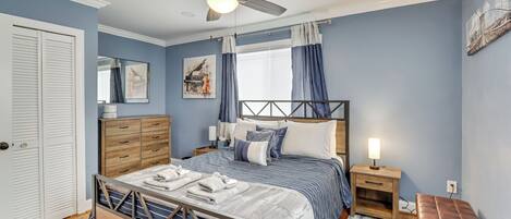 A bedroom with a bed, bedside tables, a ceiling fan, and a window with curtains.