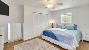 A bedroom with a bed, a ceiling fan, a window, a nightstand, and a wardrobe. - Spotless King Retreat Near Maxwell AFB (Prattville)