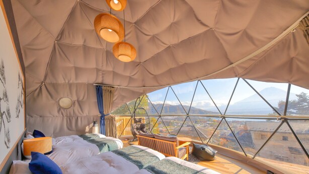 A cozy tented accommodation with a bed, hanging chairs, and a view of a mountain. - Mt.Fuji Glamping Terrace MINENOHANA (Fujikawaguchiko)