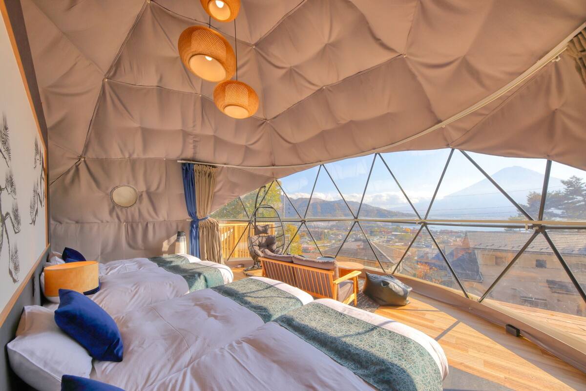 Eine gemütliche Zeltoase mit Bett, Hängestühlen und Bergblick.