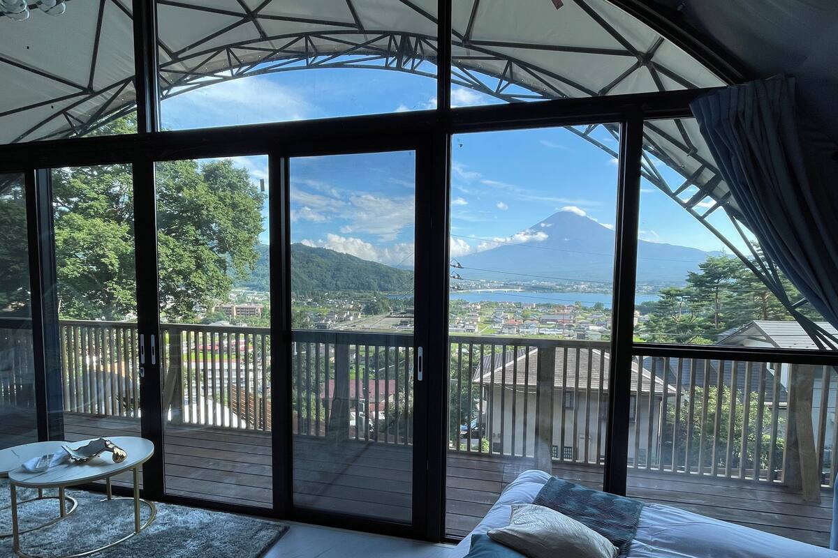 Ein Zimmer mit einer großen SchiebeglasTür, die auf einen Balkon mit Blick auf ein Gebirge und eine Stadt führt.
