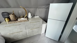 Una cocina moderna con encimera de mármol gris, refrigerador blanco y sofá gris.