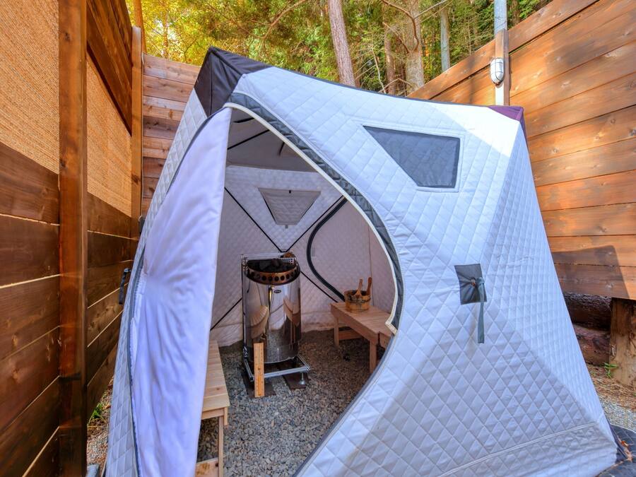 Una carpa con zona de descanso, una mesita y una silla.