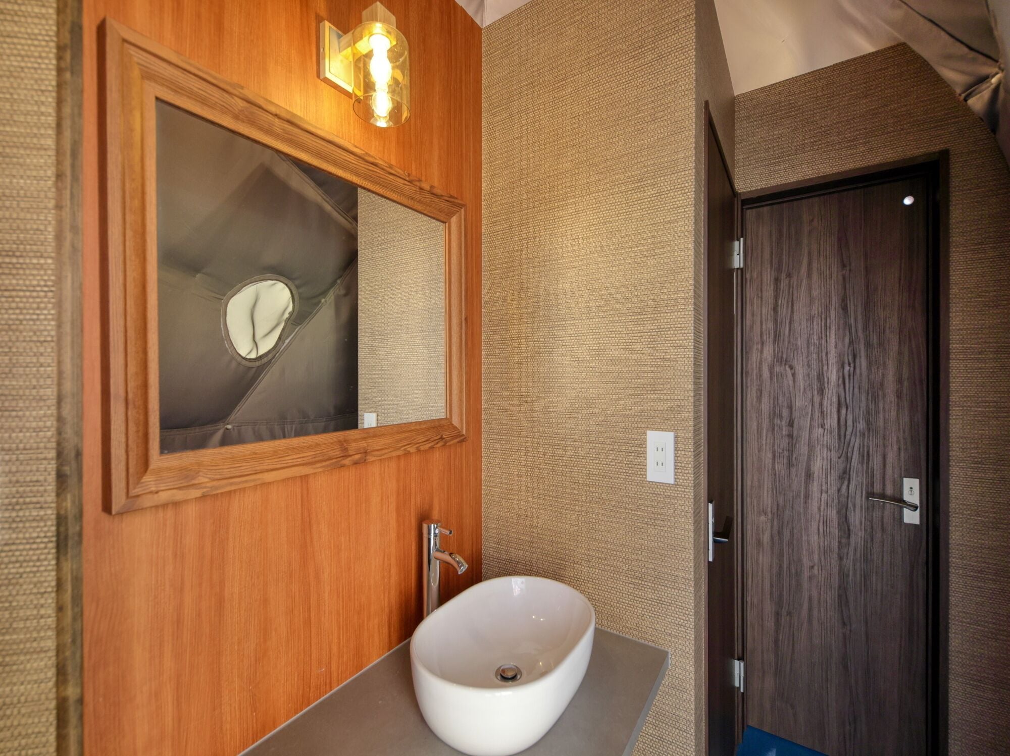 A bathroom with a wooden vanity, a white sink, a mirror, and a towel rack.
