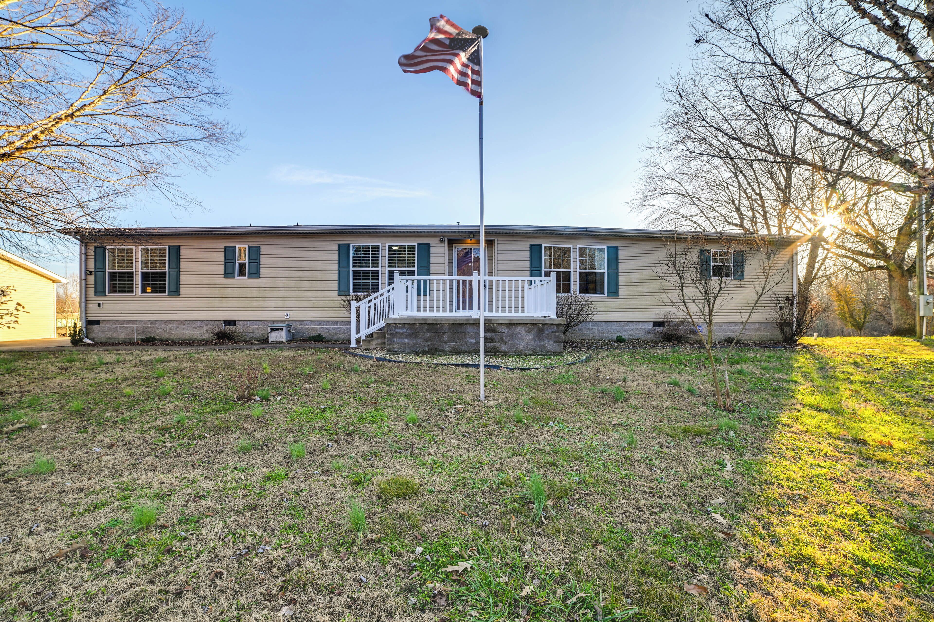 A single-story house with a front porch and a flagpole with an American flag.