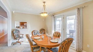 A dining room with a wooden table and six chairs, a chandelier, and a view through a glass door. - Walk to Ohio River: Golconda Home w/ Water Views! (Golconda)