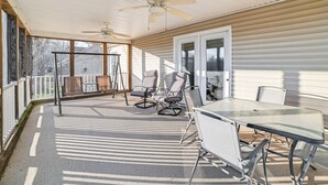 A covered patio with a table and chairs, a ceiling fan, and a view of a house through large windows. - Walk to Ohio River: Golconda Home w/ Water Views! (Golconda)