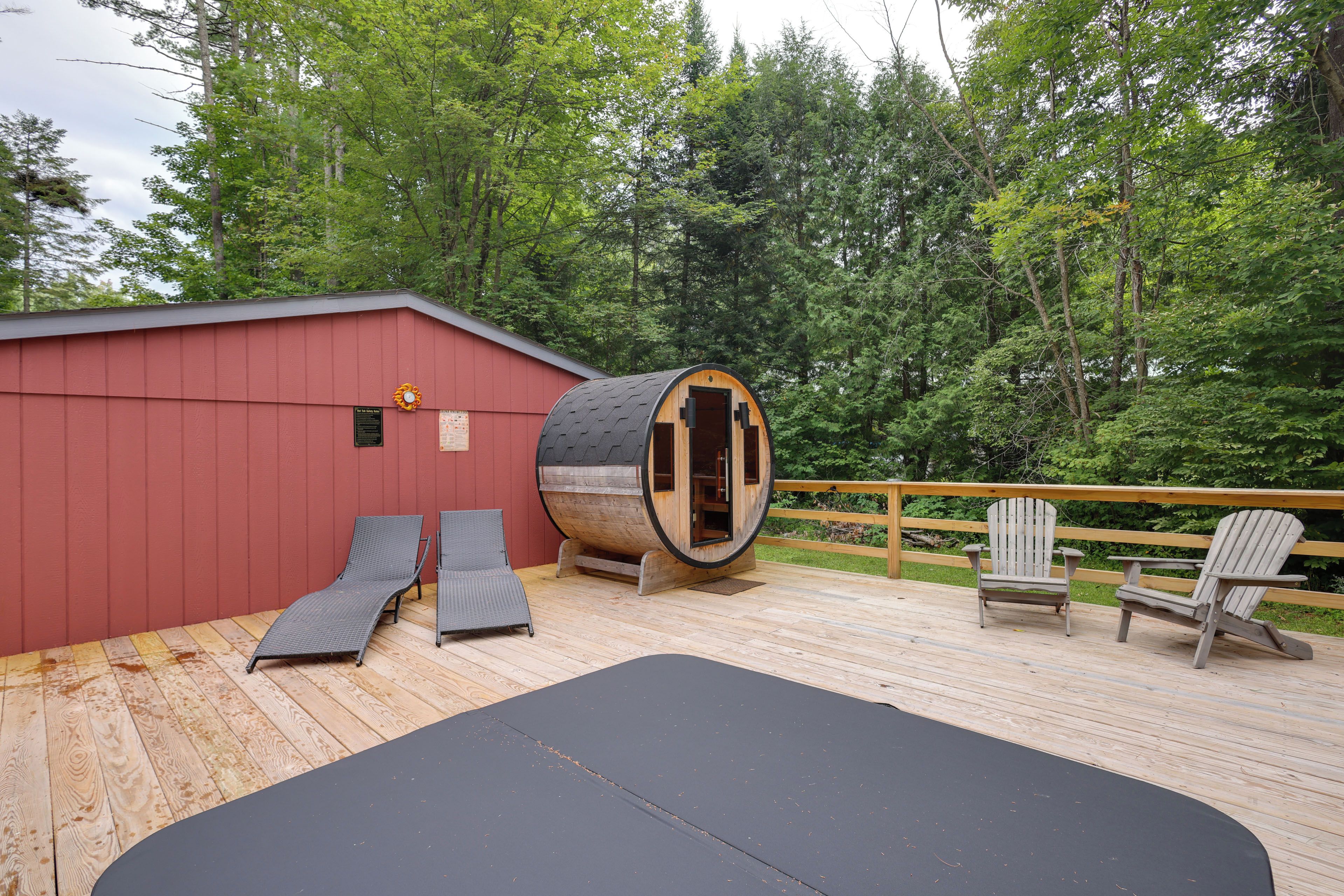 A wooden deck with a sauna, two lounge chairs, and a wooden deck chair.