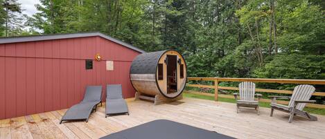 A wooden deck with a sauna, two lounge chairs, and a wooden deck chair.