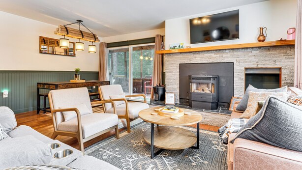 A cozy living room with a fireplace, comfortable seating, and a television mounted above it. - Forested Retreat w/ Sauna: 5 Mi to Schroon Lake (Schroon Lake)