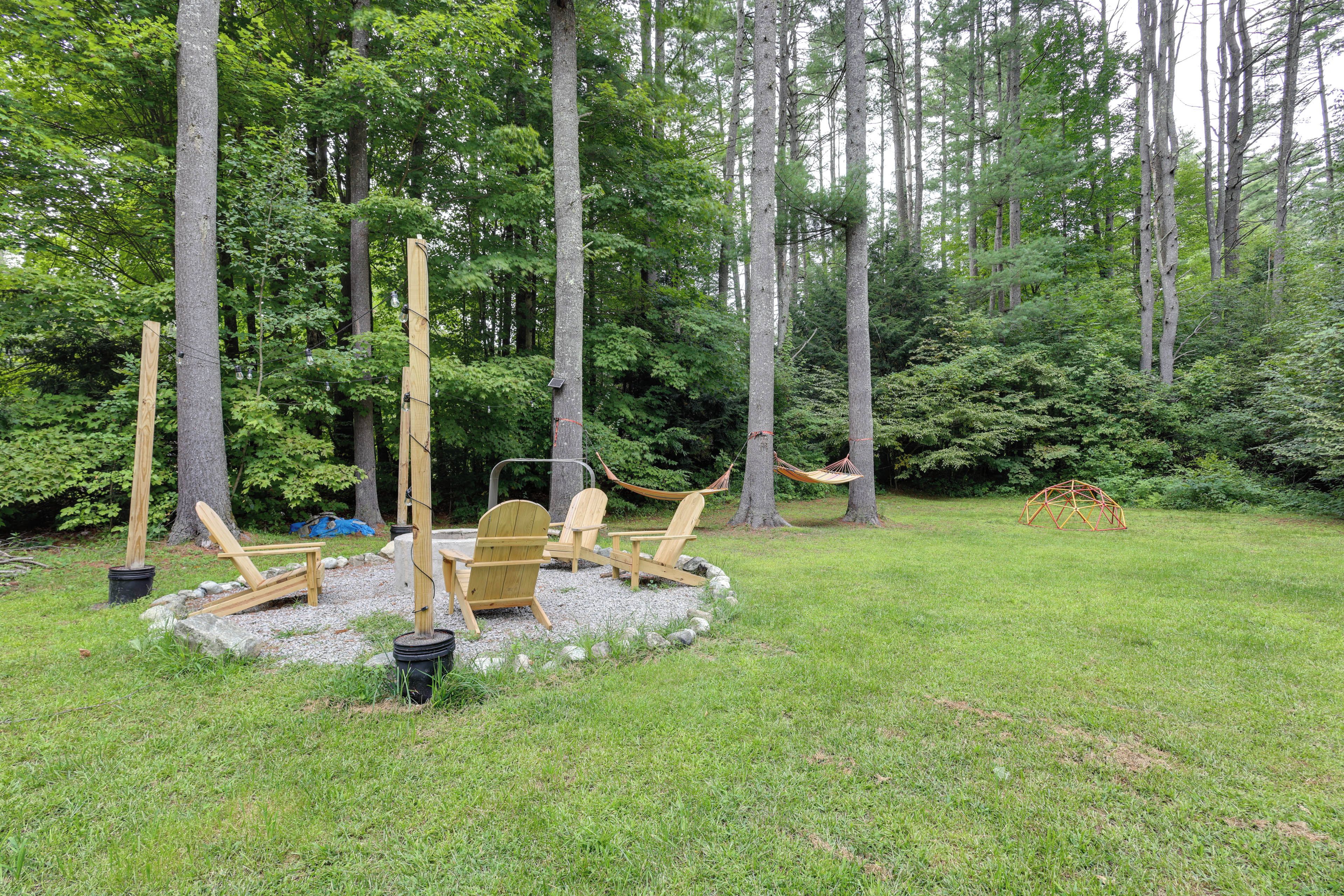 A forested outdoor area with a wooden deck, chairs, and hammocks.