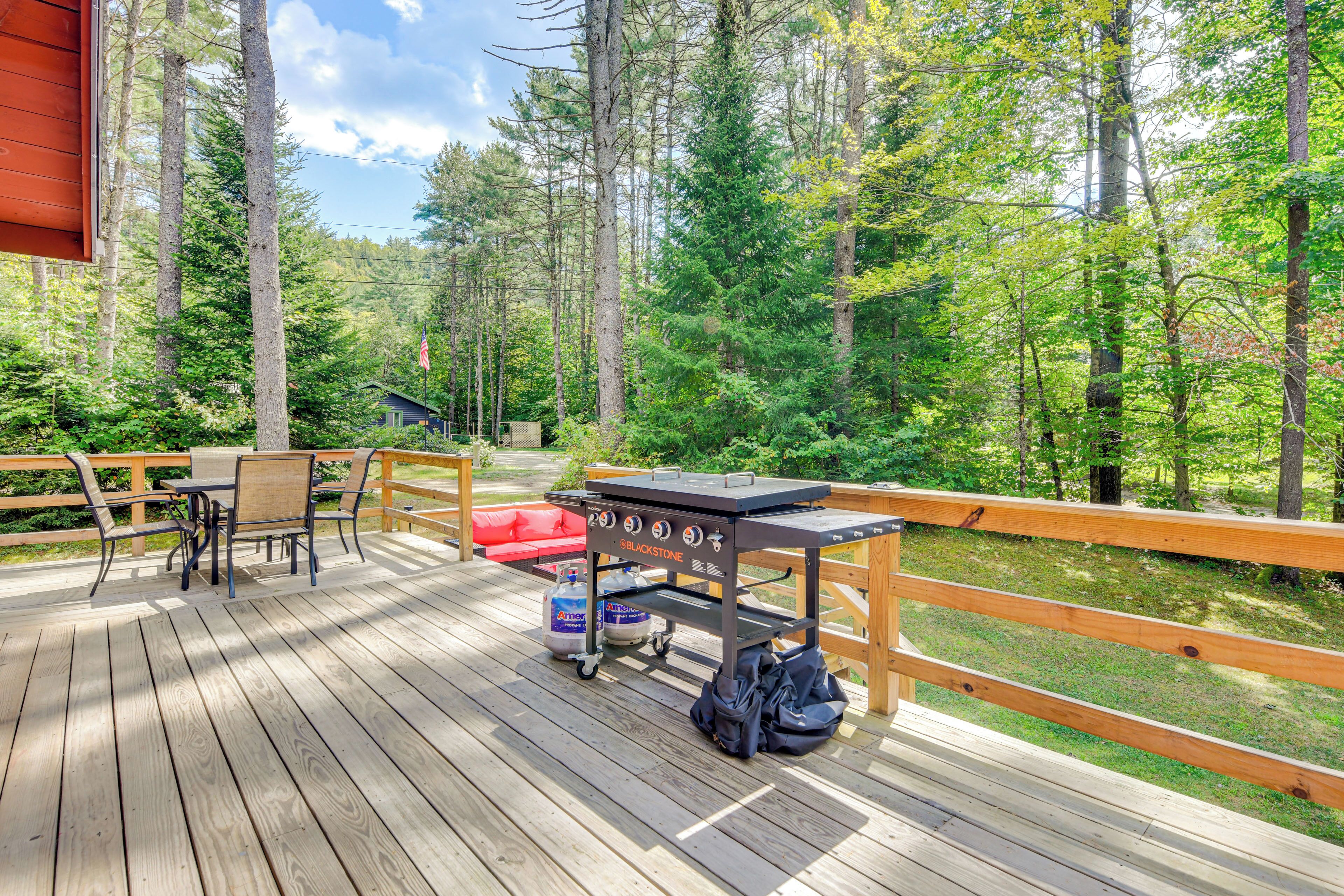 Une terrasse en bois avec un barbecue, des chaises et une table.