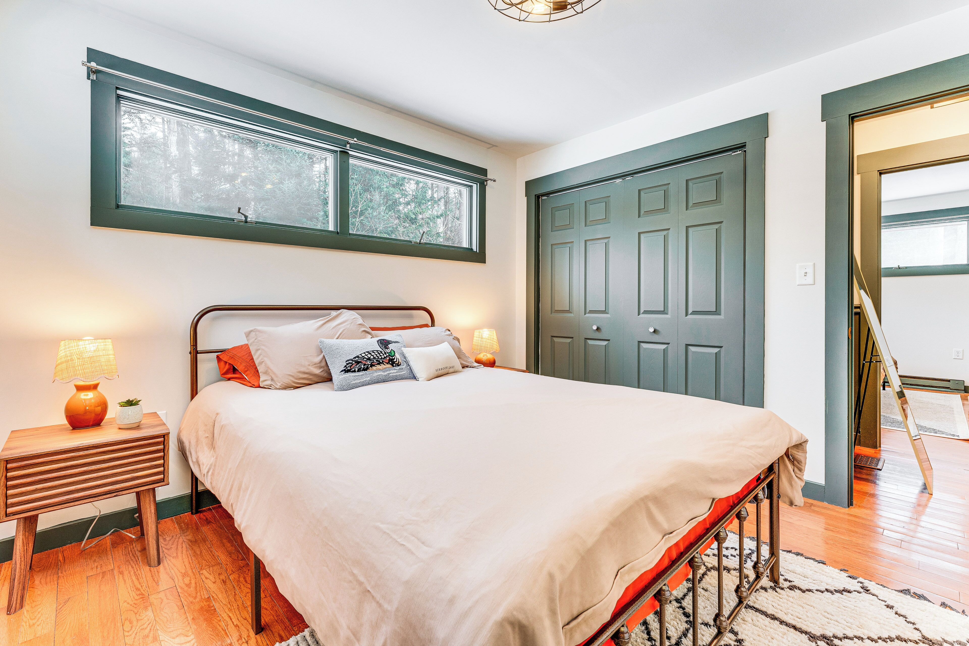 A bedroom with a bed, nightstands, a window, and a door.