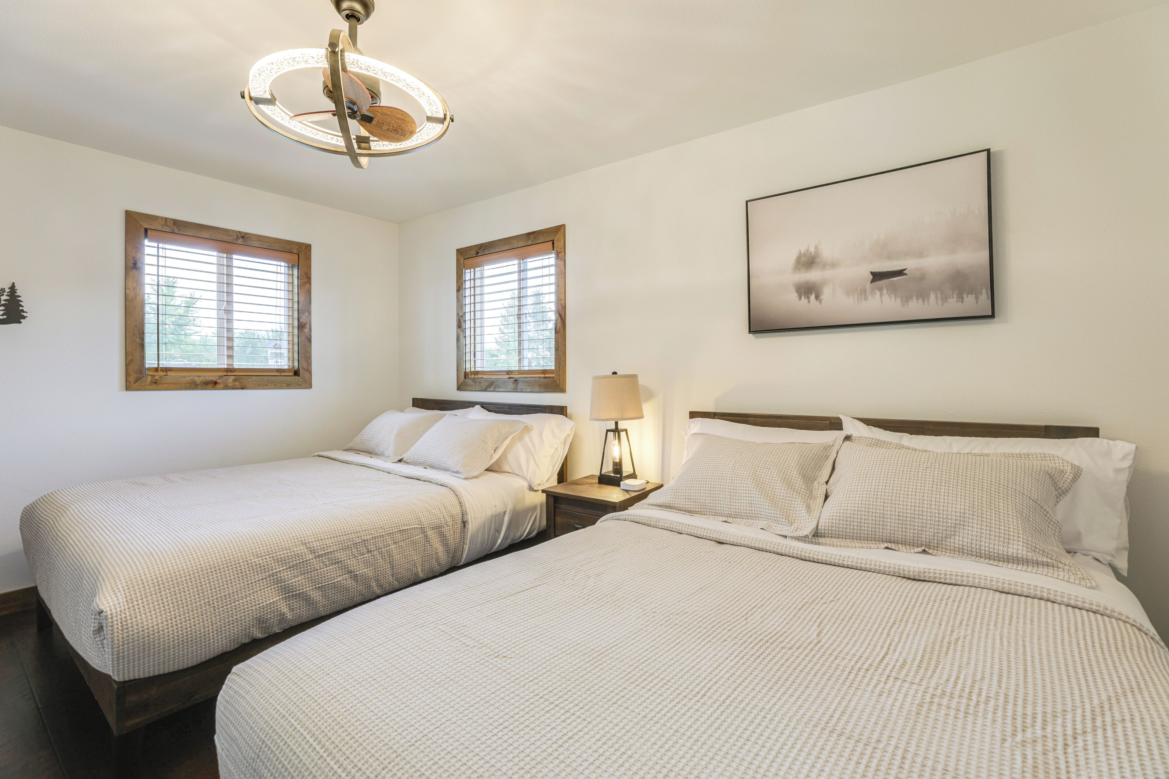 Een hotelkamer met twee bedden, houten hoofdeinden, een nachtkastje met lamp en een lijst aan de muur.