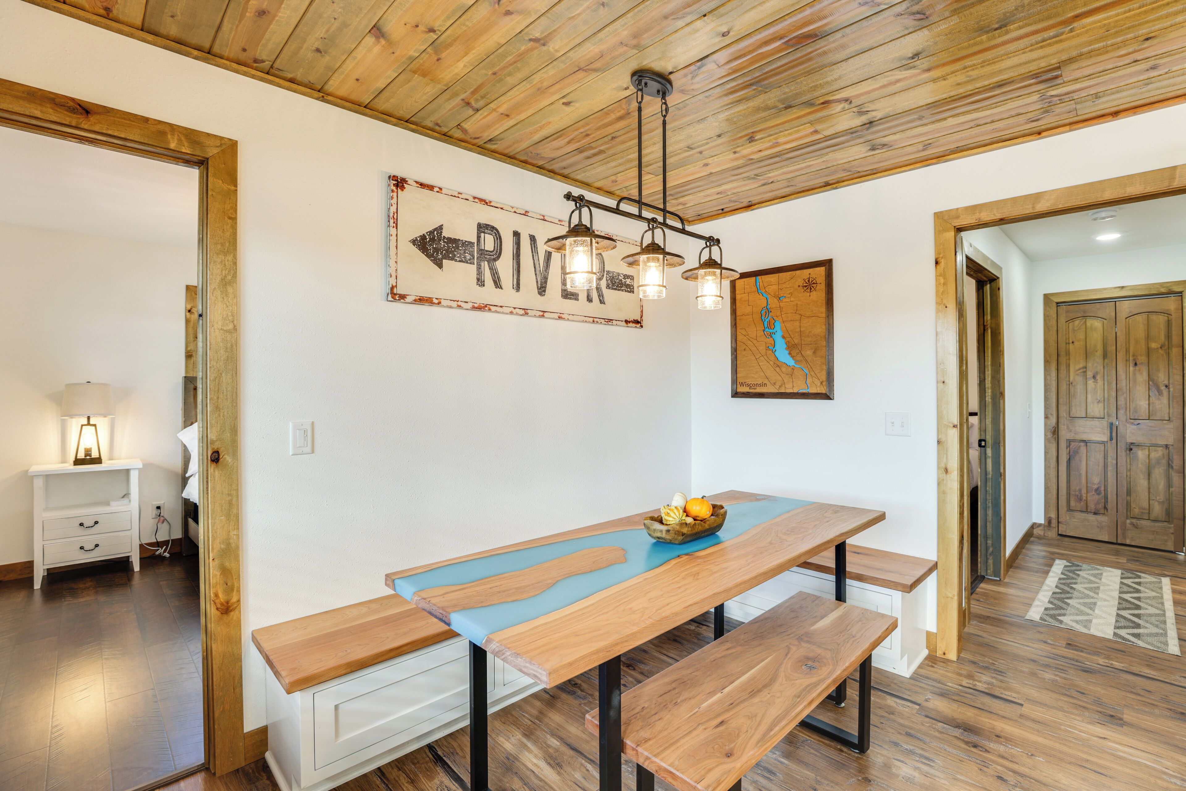 A wooden dining table with benches, a wall-mounted sign indicating 'RIVER', and a map on the wall.