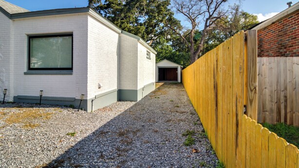 Een woonhuis met een grindpad, een gebouw van wit baksteen en een houten omheining.