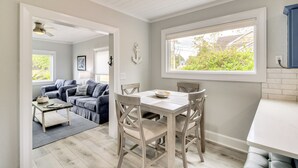 Une cuisine moderne avec une table à manger, des chaises et une fenêtre donnant sur un paysage verdoyant.