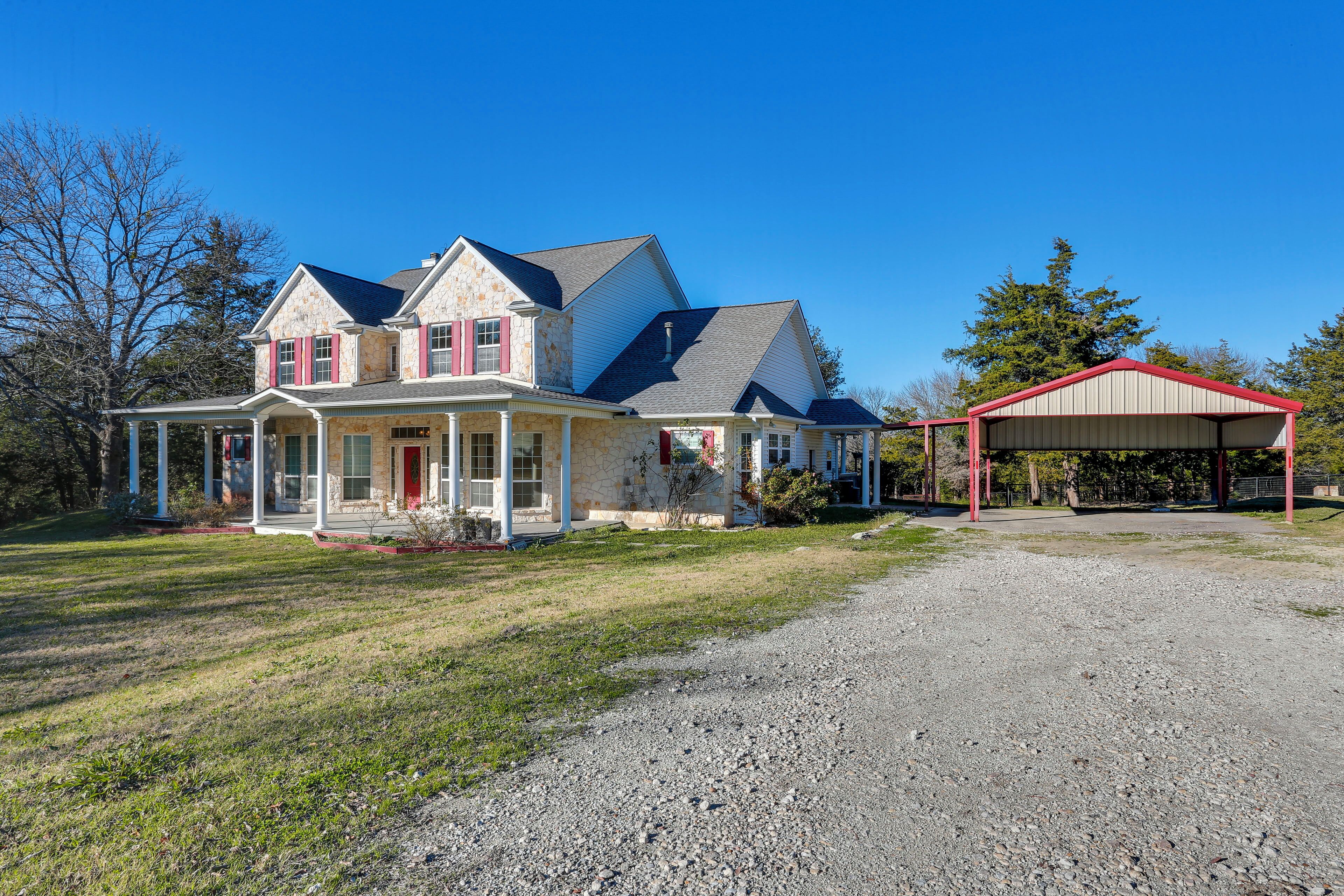 A two-story house with a covered porch and a gravel driveway.