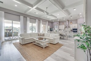 A spacious living room with a sectional sofa, a coffee table, and a large window offering a view of the outdoors.